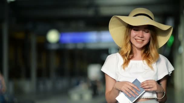 Portrait of Cute Young Girl in Summer Hat Holding Her Passport and Ticket at the Airport. Travelling Concept. Blurred Scoreboard on the Background. — Stock Video