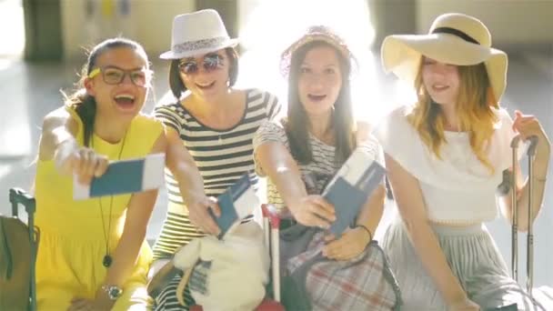 Las jóvenes felices viajarán juntas durante las vacaciones de verano. Increíbles chicas están mostrando sus documentos en la cámara esperando su avión en el Holle del aeropuerto . — Vídeo de stock