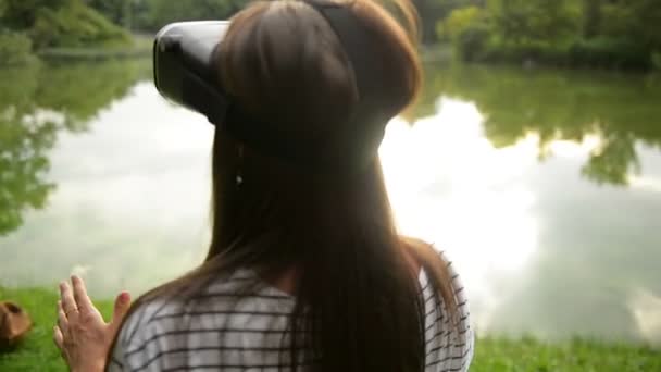 Actieve vrouwelijke tiener met lang donker haar speelt met nieuwe Virtual Reality-bril voor mobiele Gaming toepassingen in het stadspark. — Stockvideo