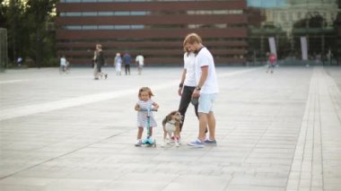 Mutlu bir aile ile bir köpek Şehir Meydanı arasında yürüyüş. Elbiseli küçük kız ile bir Scooter üzerinde gidiyor. Bir Beagle ile baba gider.