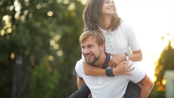 L'uomo barbuto sta appoggiando la sua ragazza ridente e la sta facendo roteare. Felice coppia avere divertimento insieme al di fuori . — Video Stock