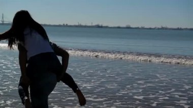 Genç komik çift sahilde Piggybacking güneş gözlüğü. Arkadaşlar eğlenmeye birlikte. Deniz arka plan üzerinde olduğunu.