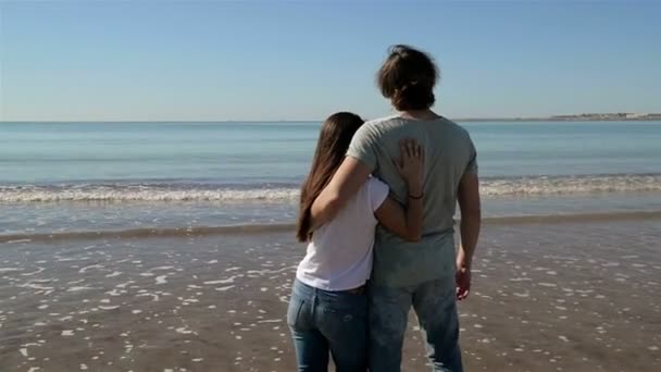Пара обіймати на тлі пляж океан Sunrise. Люди обіймаються і, дивлячись на задній зору морський пейзаж. Пара насолодитися Sunset разом. Подорожі свят відпустку. — стокове відео
