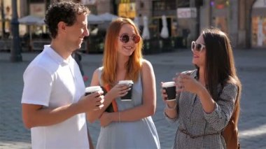 Açık havada dikey bir adam ve iki kadın kendilerini akıllı telefon ve Selfie Stick kullanarak fotoğraf çekme.