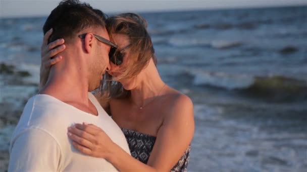 Romantiska par bär solglasögon kramas på vågor bakgrund. — Stockvideo