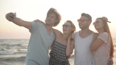 Selfie tarafından cep telefonu vakit birlikte rüzgarlı havalarda deniz alarak beyaz dişlek Smiles ile dört kişi portresi.