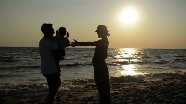 Portrait of Dark Silhouettes of Mother and Father with Little Daughter near the Sea During Sunset.