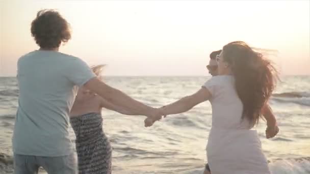 Gros plan Portrait de quatre amis souriants dansant en cercle près de la mer dans une journée chaude et venteuse sur le bouleau . — Video