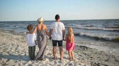 Anne, baba, oğlu ve kızı Holding eller Beach sırasında güneşli rüzgarlı gün denize yakın portresi. Arkadan Görünüm.