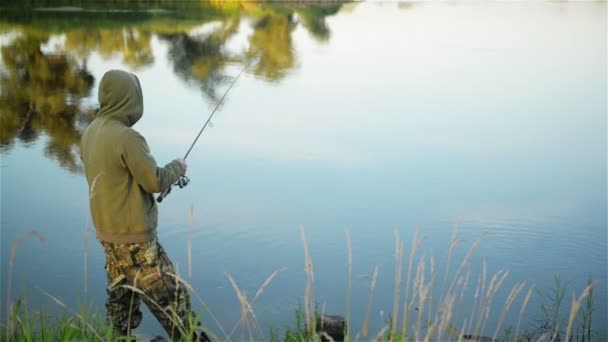 Fisk-man fiske över sjön under våren. Ensam fiskare bor ensam omgivet av natur. Han har en vila. — Stockvideo