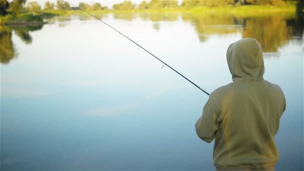 Fish-man fishing over the lake in the spring. Solitary angler staying alone surrounded by nature. He has a rest. — Stock Video