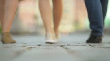 Üç arkadaş öğlen kaldırımda yürüyor. Onlar Are Having Fun şuna güneşli ve ısı hava.