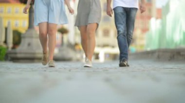 Üç arkadaş öğlen kaldırımda yürüyor. Onlar Are Having Fun şuna güneşli ve ısı hava.