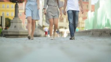 Üç arkadaş öğlen kaldırımda yürüyor. Onlar Are Having Fun şuna güneşli ve ısı hava.