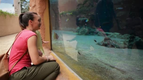 Gelukkig moeder met haar dochter op zoek bent in Aquarium met de vissen. Ze hebben een heleboel plezier die dit moeders dag. — Stockvideo