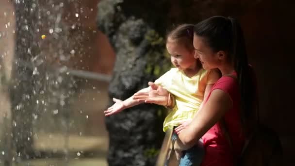Matka a dcera Cutie hraje s malým vodopádem. Oni mají hodně zábavy v den matek společně. Vodopád je na pozadí. — Stock video