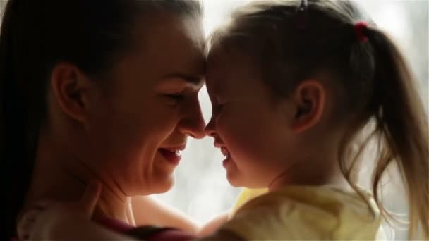 Madre y su hija se acurrucan. La lluvia está en segundo plano. Se están divirtiendo mucho porque hoy es el día de las madres . — Vídeos de Stock