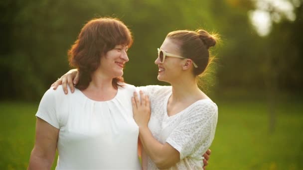 Mor och dotter är på en äng. De har mycket roligt eftersom idag är mors dag. De är omgivna av grönt gräs. — Stockvideo