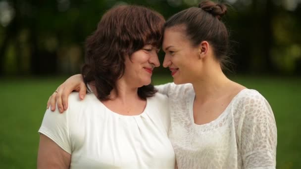 Mooie moeder en dochter knuffelen elkaar op een zonnige dag buiten. Ze hebben een heleboel plezier want vandaag is Mothers Day. — Stockvideo