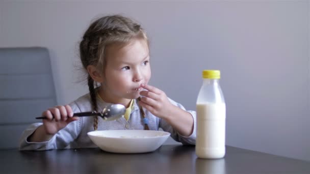 부엌, 아이들의 식욕, 아이들의 음식. 귀여운 여자 애가 죽을 먹고 있어. 건강에 좋은 식사 요리 — 비디오
