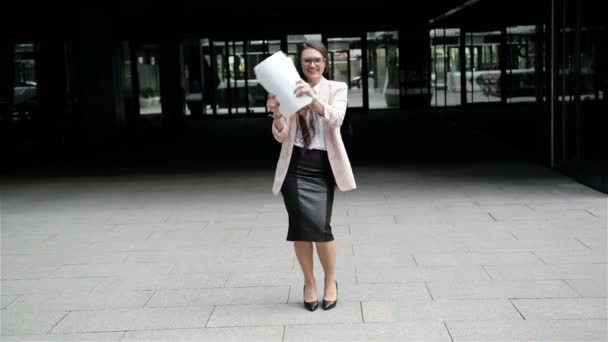 Успешная молодая кавказская деловая женщина поднимает руки с папкой документов на градостроительном фоне . — стоковое видео