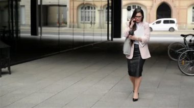 Gözlüklü genç bir stresli Iş kadını telefonda belgeler ve görüşmeler Ile şehir üzerinden gider. O stres Için onun kağıtları Drops.