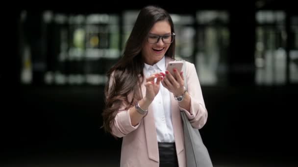 Happy Business Woman utiliza un teléfono inteligente de pie en la calle. Ella está recibiendo buenas noticias. Teléfono Hablando — Vídeos de Stock