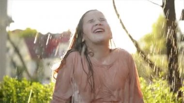 Genç mutlu kız yağmur altında eğleniyor. Gülümseyen Islak Çocuk Gülümse ve açık havada keyifli ol..