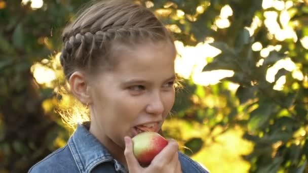 Söt flicka porträtt bo i äppelträd trädgård utomhus äta mogna saftiga frukter — Stockvideo