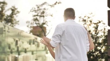 Şehir siluetiyle dans eden genç bir çift ve arka planda günbatımı güneşi. Yavaş çekim, 4k