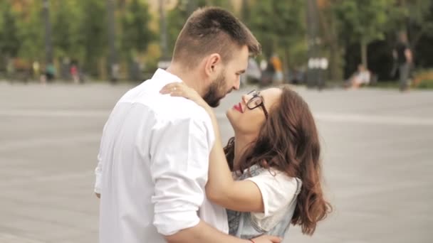 愛情深い若いカップルは、街の通りで一緒に立っている間、ロマンチックなキスを抱きしめ、共有します — ストック動画