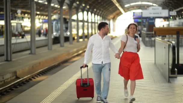 Running paar met een koffer in een trein station. Vrouw die paspoorten in haar handen houdt. — Stockvideo