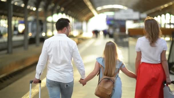 Ung familj med söt dotter, promenader på järnvägsplattform innehar resväska. Bästa resa och semester koncept. Kaukasiskt utseende. — Stockvideo