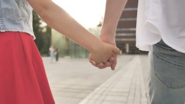 Aşık genç çift şehirde el ele yürüyor. Romantik ruh hali