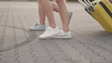 Tatil de seyahat. Bavulları avludan yuvarlaan iki kadının bacakları. Tatilde birlikte seyahat eden bayan arkadaşlar.