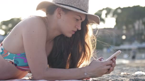 Profil žena textilie v chytrý telefon na pláži s mořem v pozadí — Stock video