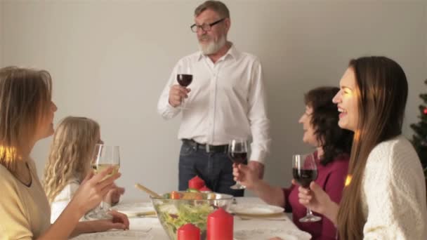 Семья, сидящая за столом, кушающая, общающаяся и развлекающаяся во время семейного ужина. Семейный тост за обеденным столом дома — стоковое видео