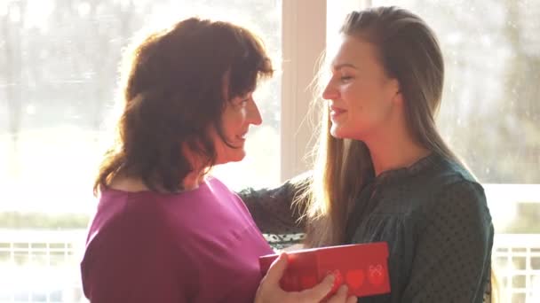Kochająca dorosła córka prezentująca wiosenne kwiaty szczęśliwej starej matce śmiejącej się z przytulania, młoda kobieta gratulująca przytulanej mamie w średnim wieku. Dzień Matki w domu — Wideo stockowe