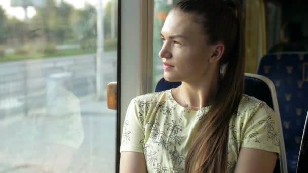 Fiatal nő kinézet a vonat ablak. Lány gondolt valami ülés közelében az ablakon a városi vasút alatt, sem a napi ingázik. Lassított mozgás — Stock videók