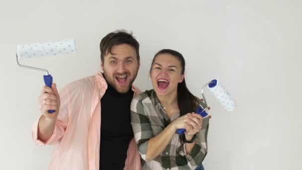 Mann und Frau haben die Wände gestrichen, schöne junge Familie feiert das Ende der Reparatur — Stockvideo