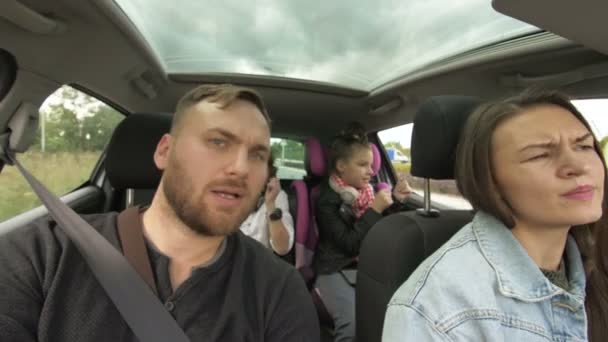 Man and woman with children driving in car, two parents and children traveling and dancing in tre transport. Happy family, road trip — Stock videók