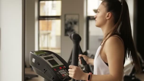 Aantrekkelijke jonge fitness model werkt op opleiding apparaat binnen in fitnesscentrum — Stockvideo