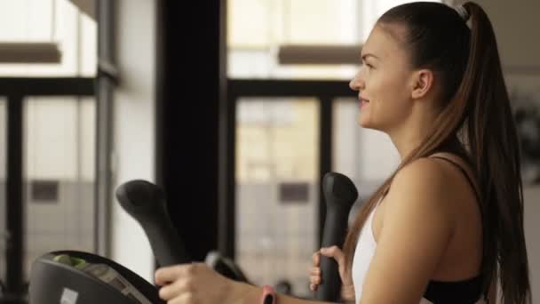 Fitness kvinna träningsben muskler på sport simulator i gym. Koncentrerad tjej som tränar på idrottsförening. — Stockvideo