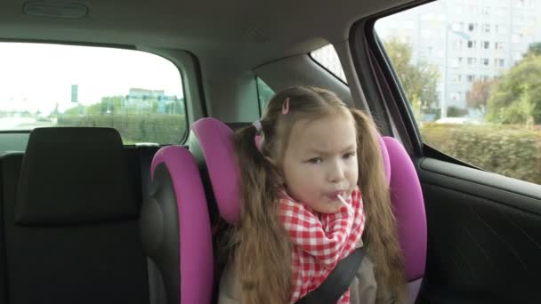 Child in the backseat of a car traveling on road, looking out window daydreaming — Stockvideo