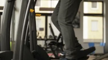 Çekici yaşlı beyaz kadın antrenman makinesinde çalışıyor ve fitness merkezinde mutlu görünüyor. Orta yaşlarda spor ve spor