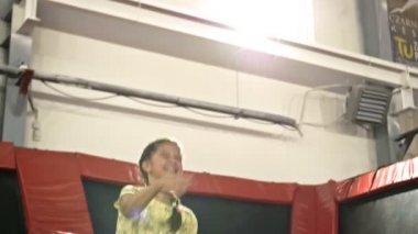 Okul çağındaki tatlı kız trambolinde zıplıyor. Çocuk mutlu..