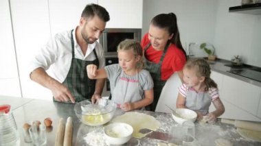 Modern bir iç mekanı olan bir mutfakta birlikte yemek pişiren sevimli bir aile. Kardeşler ailelerine yardım etmekten mutluluk duyar..