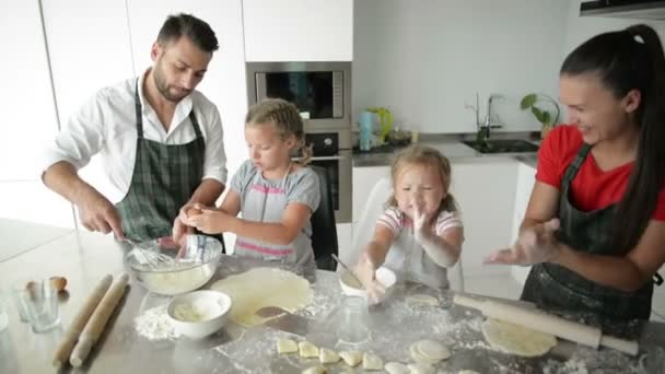 Familj med fyra skulpterar dumplings i köket. Systrar älskar att hjälpa föräldrar. — Stockvideo