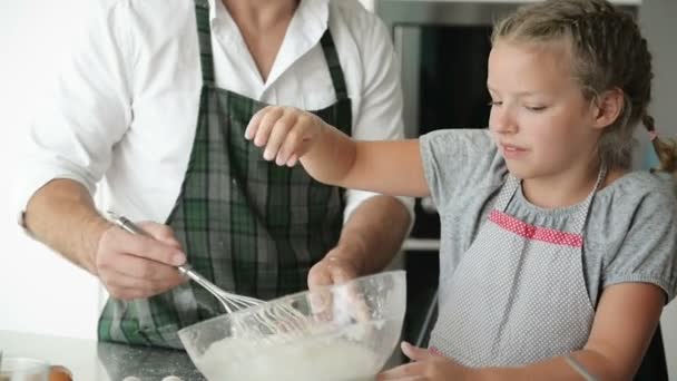 Táta a dcera něco vaří v kuchyni. Dívka pomáhá otci. — Stock video