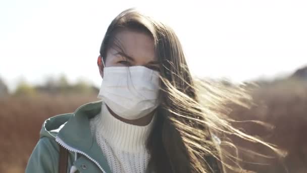 Retrato de la joven mujer caucásica quitándose la máscara de la boca. Chica usando una máscara protectora al aire libre — Vídeo de stock